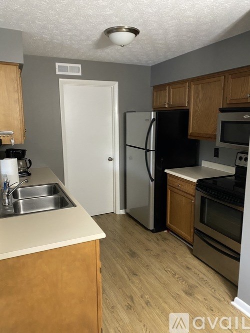 A kitchen with wooden cabinets and a black fridge.