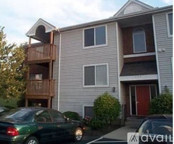 A two-story building with a balcony and a car parked in front.