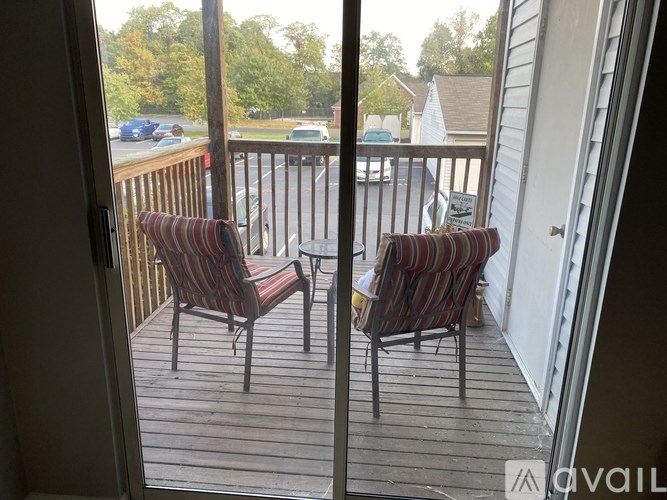 A balcony with two striped chairs and a small table.