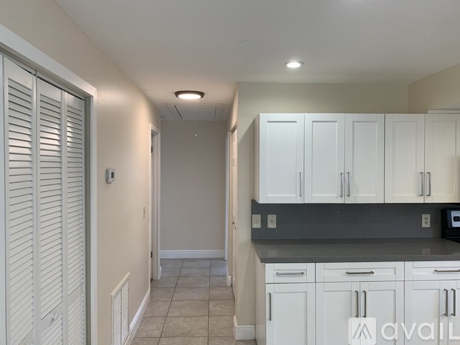 A kitchen with white cabinets and a tiled floor.