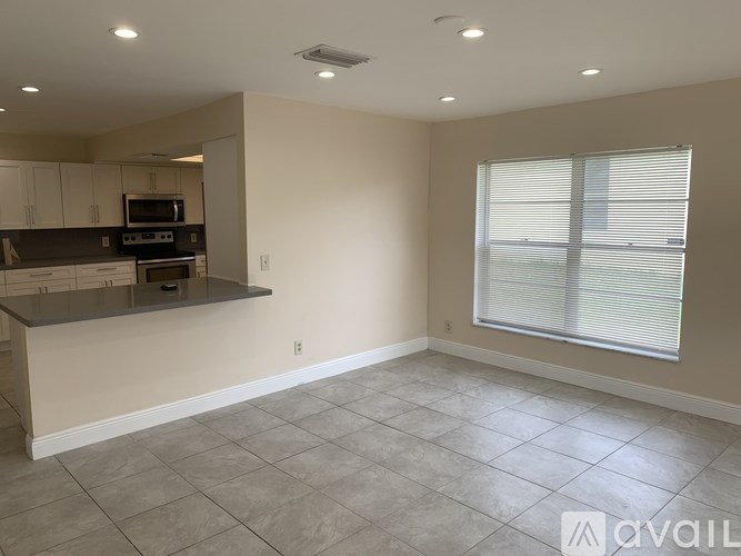 A spacious kitchen with a countertop and a window with blinds.