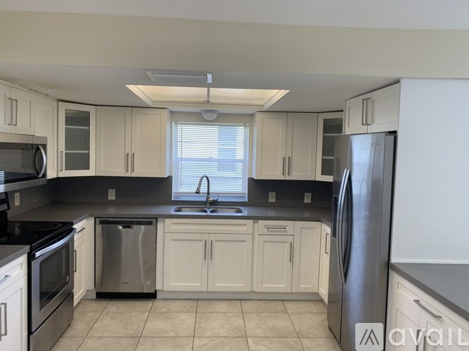 A kitchen with white cabinets and a black countertop.
