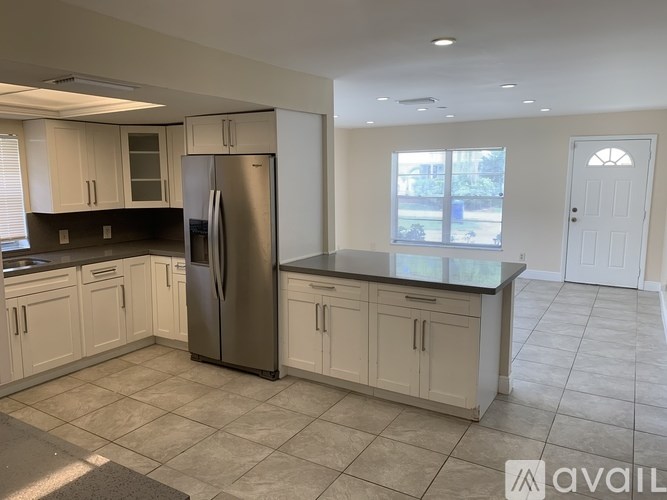 A kitchen with a refrigerator, cabinets, and a countertop.