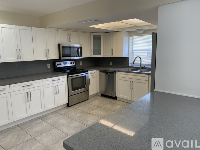 A kitchen with white cabinets and a black countertop.