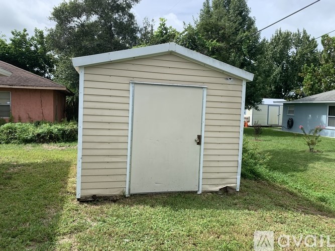 A shed with a white door is situated in a grassy area.