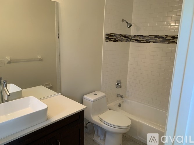 A white toilet is in a bathroom with a white sink and a shower.