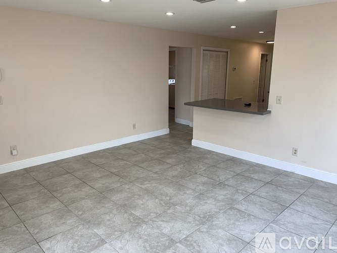 A spacious room with a tiled floor and a bar area.