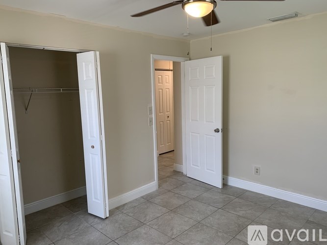 A room with a ceiling fan and two doors, one of which is open.