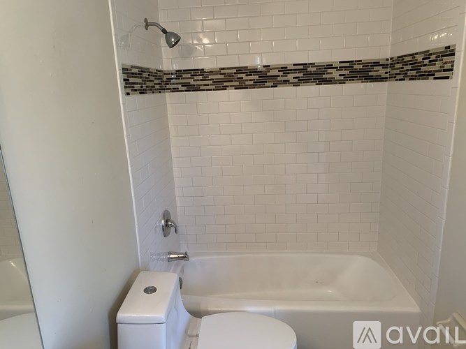 A white toilet sits next to a white bathtub in a bathroom.