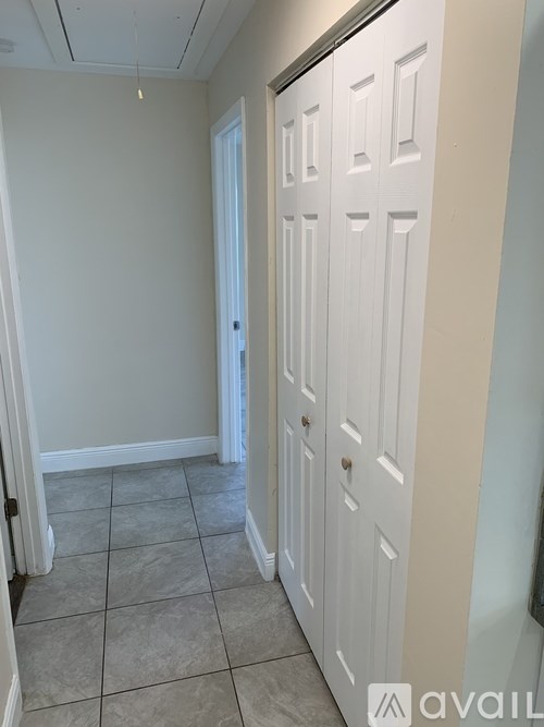 A white door is on the right side of a room with a tiled floor.