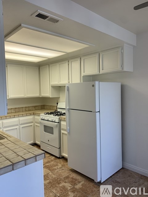 A kitchen with a white refrigerator and a white stove top oven.