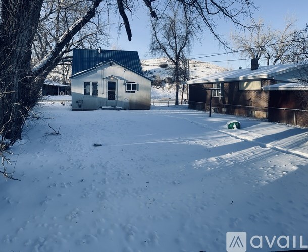 A house with a snow-covered ground and trees in the background.