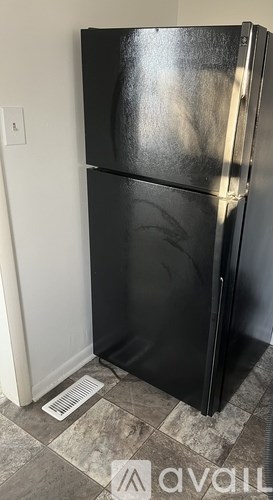 A black fridge in a room with a tiled floor.