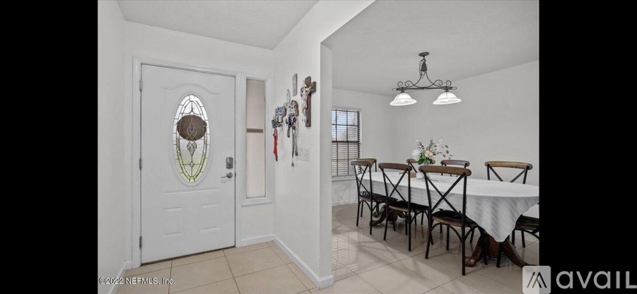 A dining room with a white door and a chandelier.