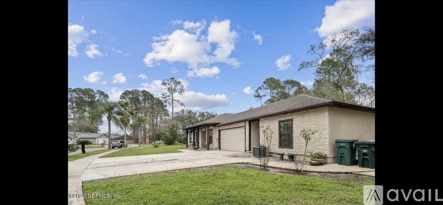 A house with a driveway and a tree in front of it.