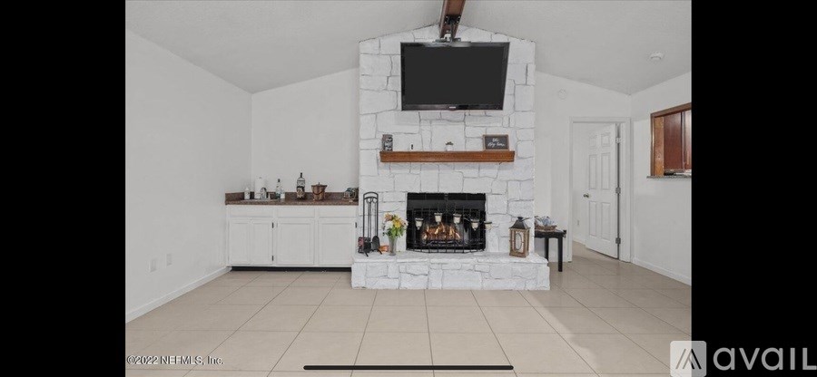 A living room with a fireplace and a television mounted above it.