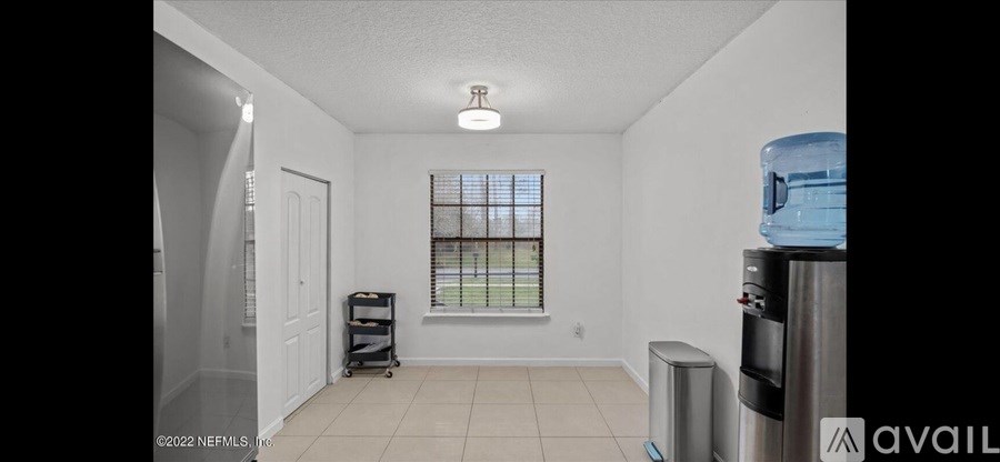 A white room with a window and a fridge.