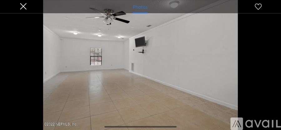 A spacious room with a ceiling fan and a flat-screen TV mounted on the wall.