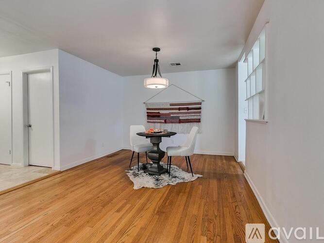 A room with a wooden floor and a table with chairs.