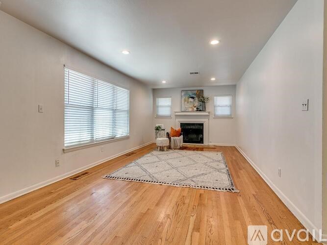 A spacious room with wooden floors and a fireplace.