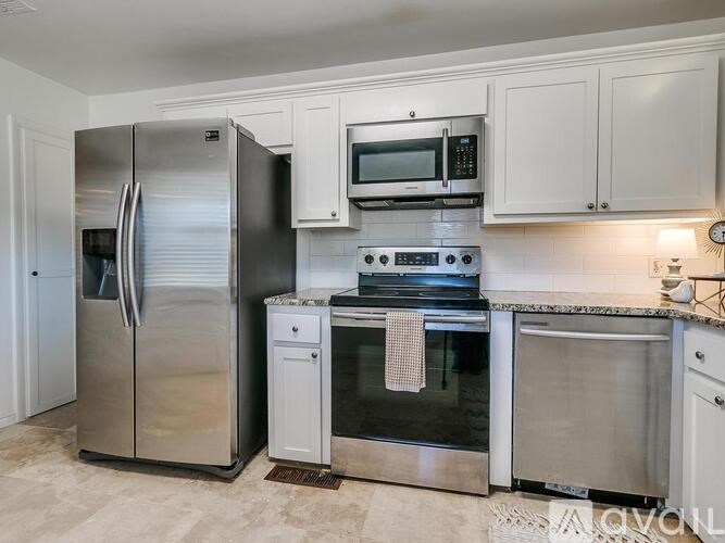 A kitchen with a stainless steel refrigerator, microwave, oven, and cabinets.
