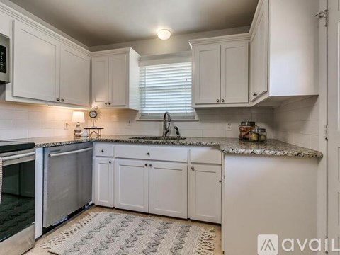 A kitchen with white cabinets and a granite countertop.