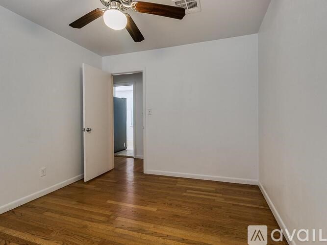 A room with a ceiling fan and wooden flooring.