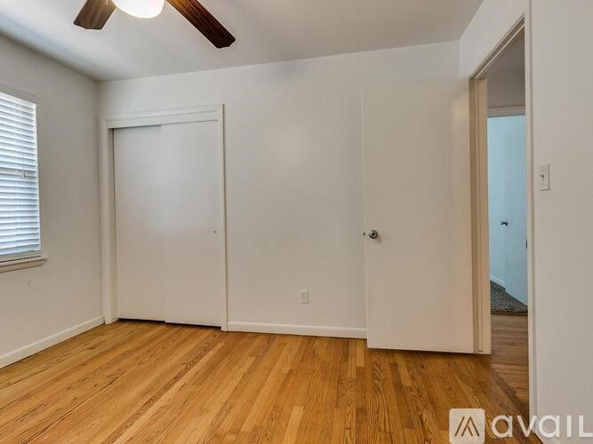 A room with a ceiling fan and wooden flooring.