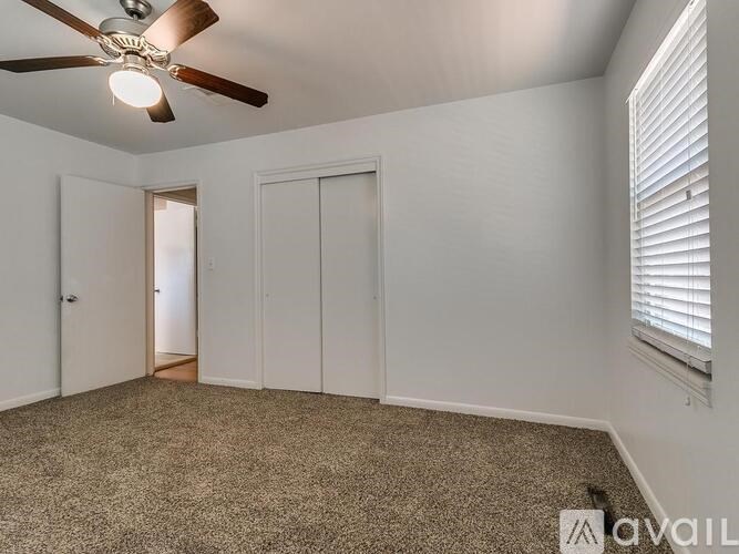 A room with a ceiling fan and carpeted floor.