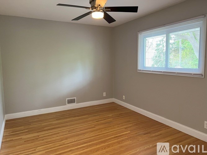 A room with a ceiling fan and a window with blinds.