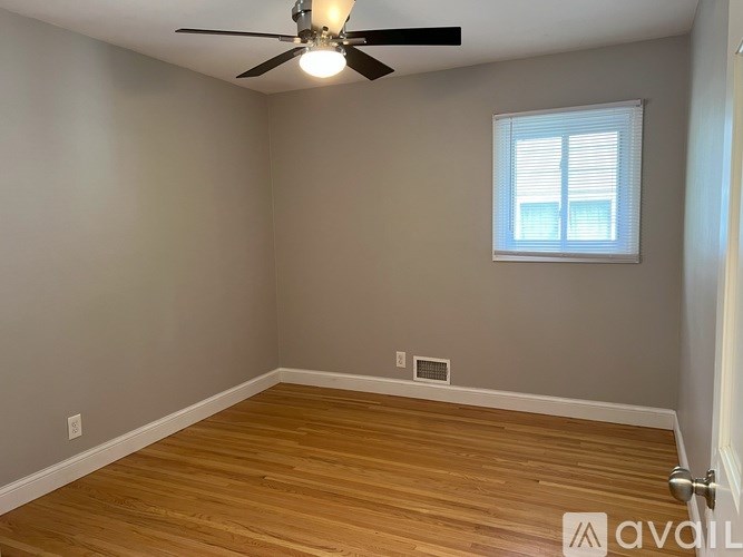 A room with a ceiling fan and a window with blinds.