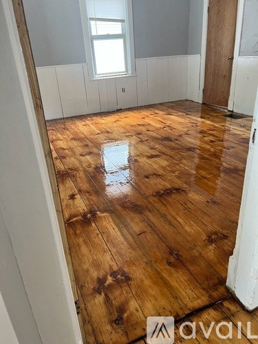 A room with wooden flooring and white walls.