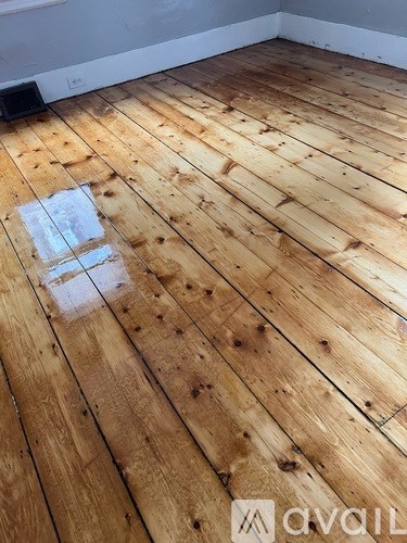 A room with wooden flooring and a logo that reads "AVAIL".
