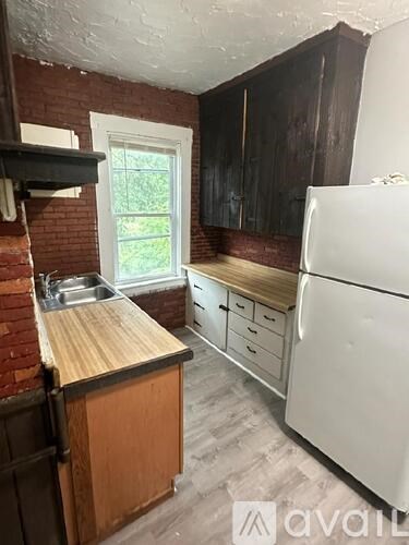 A kitchen with a white refrigerator, wooden countertops, and a window.