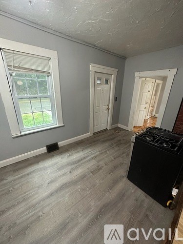 A room with a window, a door, and a suitcase on the floor.