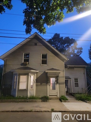 A house with a front porch and a tree in front of it.