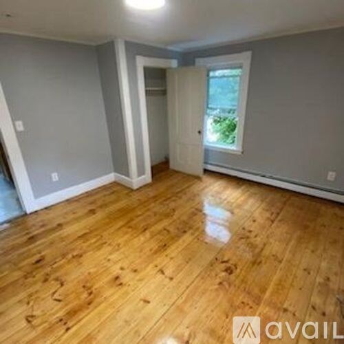 A room with wooden flooring and a doorway leading to another room.
