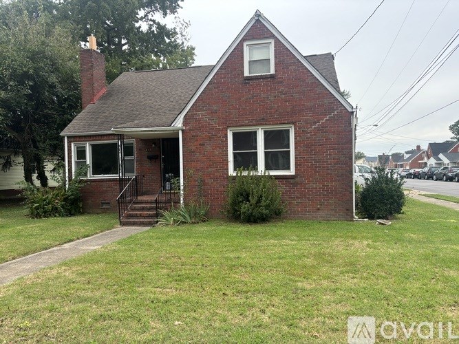 A small red brick house with a white window and a black door.