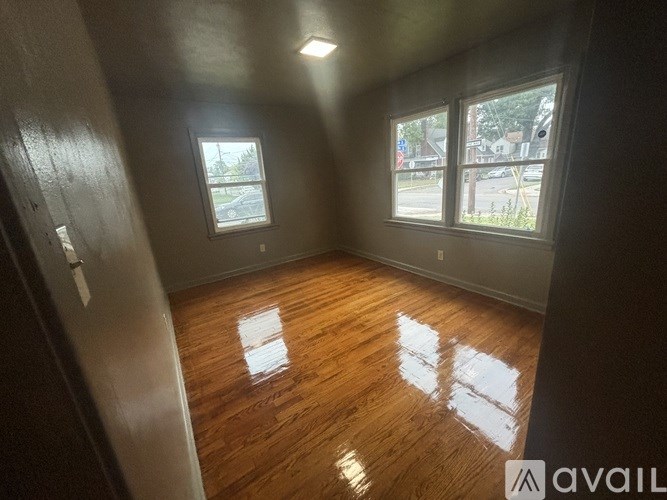 A room with wooden floors and two windows.