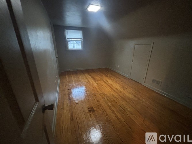 A room with wooden flooring and a window showing a house outside.