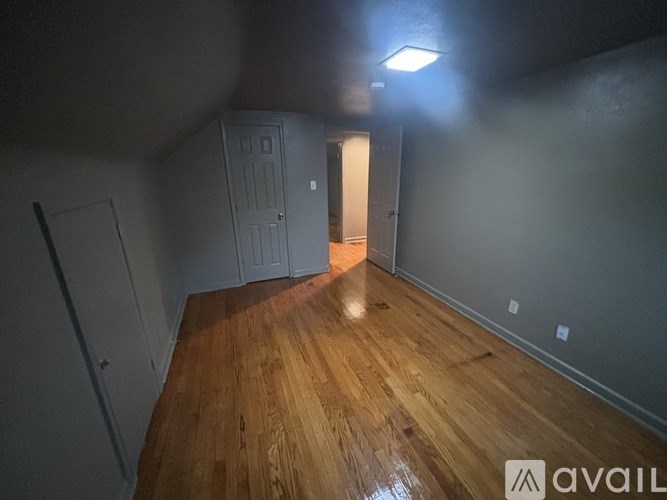 A room with wooden floors and a door in the background.