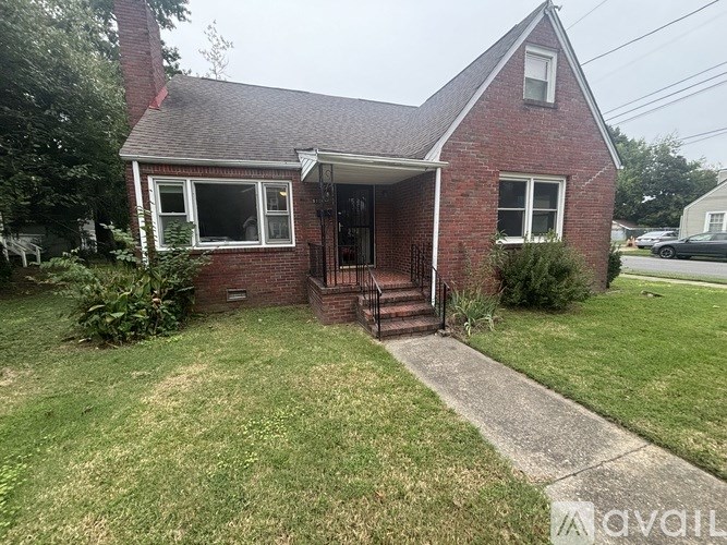A brick house with a porch and a green lawn.