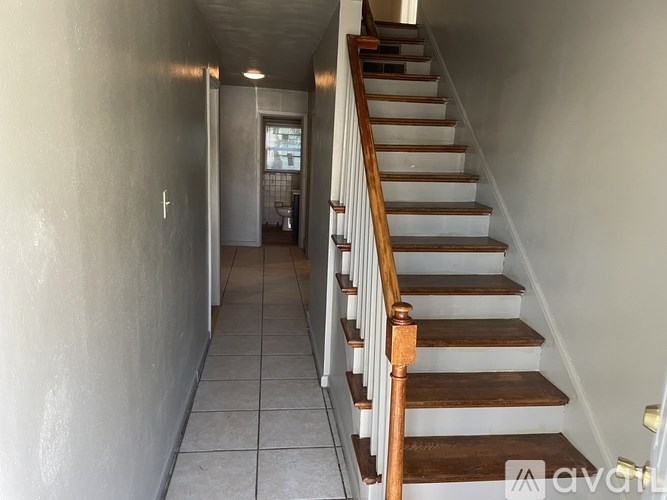 A hallway with a staircase leading to a bathroom.