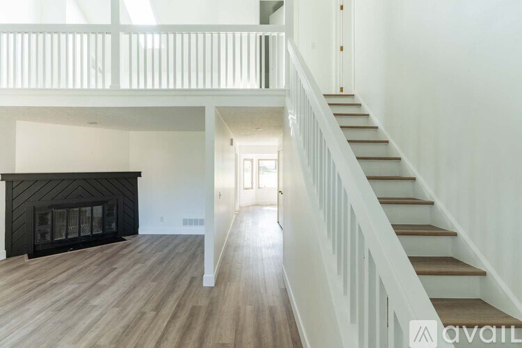 A spacious living room with a fireplace and a staircase leading to the upper floor.