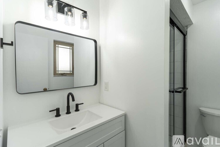 A bathroom with a sink, mirror, and a shower.