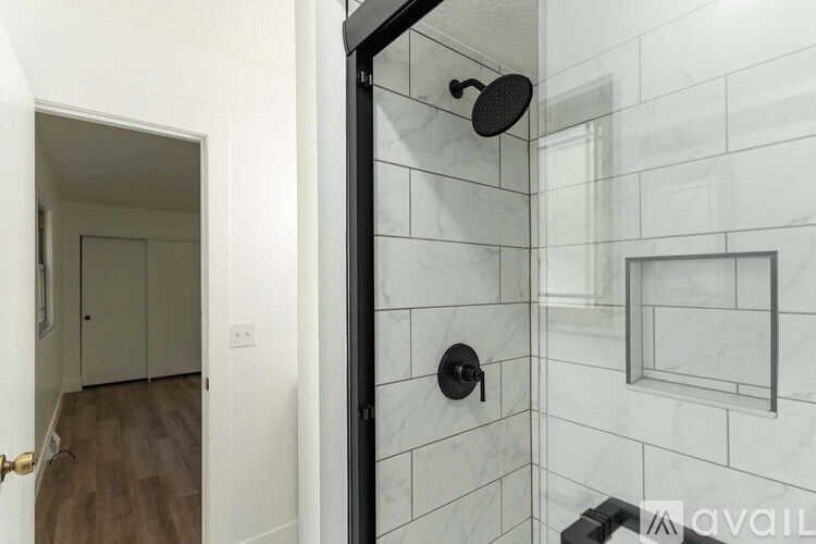 A bathroom with a walk-in shower and a doorway leading to another room.