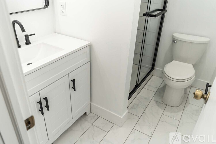 A white bathroom with a toilet, sink, and cabinet.