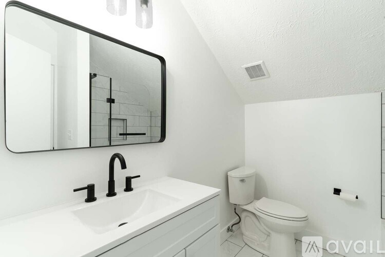 A bathroom with a sink, toilet, and mirror.