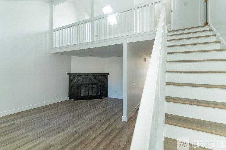 A living room with a fireplace and a staircase.