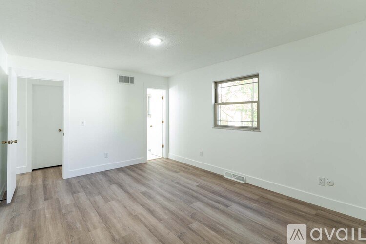 A room with wooden flooring and a window on the right side.